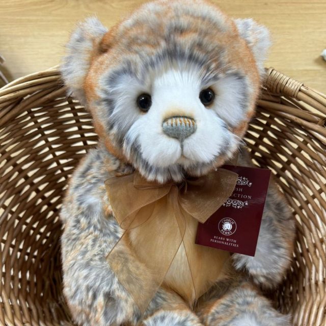 Charlie Bears Rhys Plush Collection Charlie Bears Rhys plush bear seated inside a wicker basket with orange bow