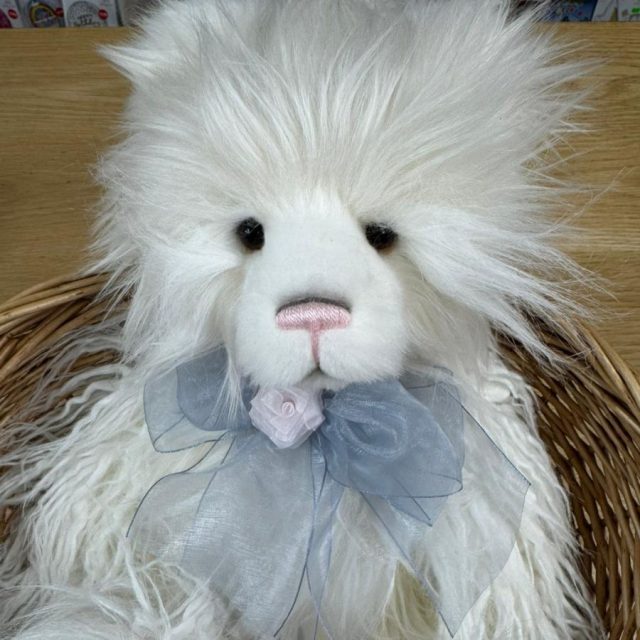 Detailed front view of Charlie Bears Charmaine bear's face showcasing cream plush fur and blue satin bow
