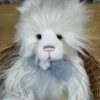Detailed front view of Charlie Bears Charmaine bear's face showcasing cream plush fur and blue satin bow
