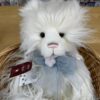 Close-up of Charlie Bears Charmaine cream plush bear's face with blue satin bow and attached tags