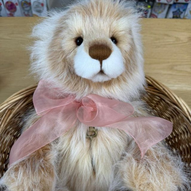 Daybreak Charlie Bears Charlie Bears Daybreak plush bear wearing a large pale pink bow seated in a wicker basket