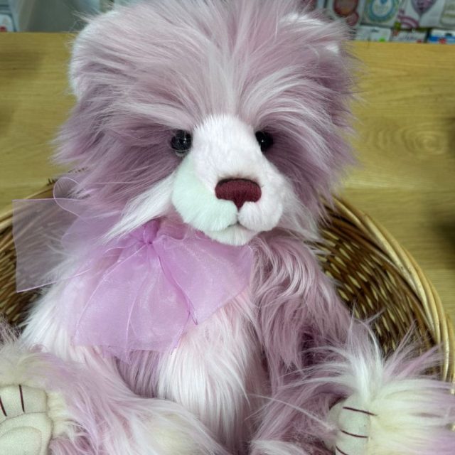 Keeper of Secrets Close-up of Charlie Bears Keeper of Secrets with fluffy purple and cream fur sitting in a wicker basket