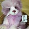 Keeper of Secrets Charlie Bears Front view of Keeper of Secrets plush bear with tag and purple bow sitting in wicker basket