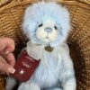 Plus Collection Gaynor Close-up of Charlie Bears Gaynor plush bear holding a red Plush Collection tag