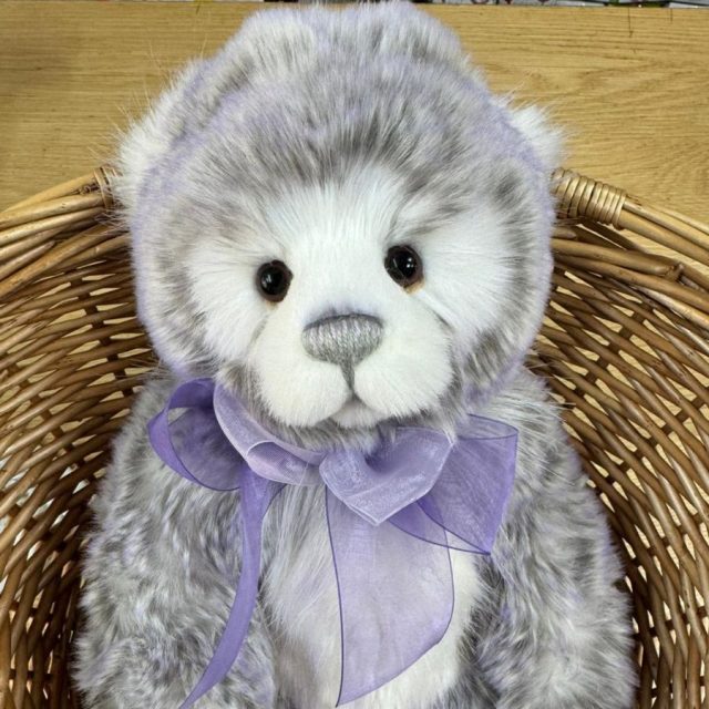 Plush Collection Meghan Close-up of Charlie Bears Meghan plush bear sitting in basket with lilac bow