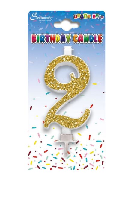 Gold glitter number 2 birthday cake candle with holder on colourful confetti background