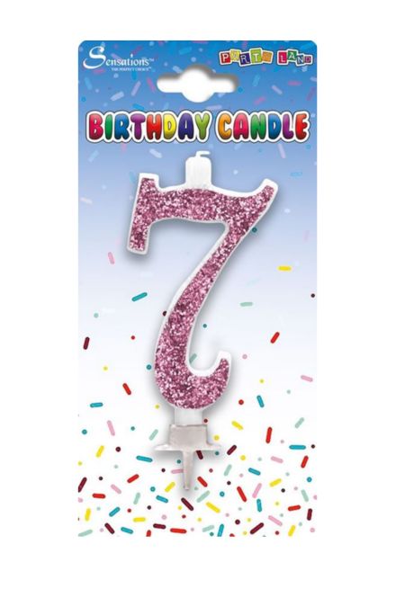 Pink glitter birthday cake candle shaped as number 7 on a party-themed card