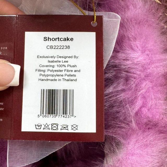 Charlie Bears Shortcake tag with care instructions and product details held by hand