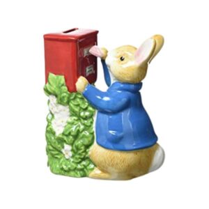Peter Rabbit money bank posting a letter into a red post box surrounded by green foliage