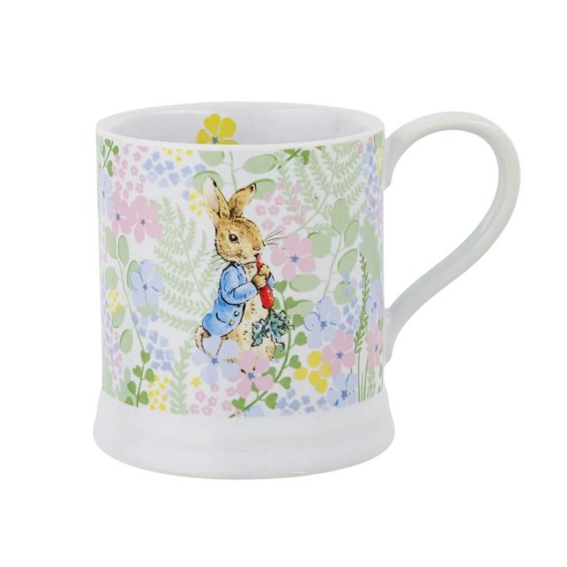Peter Rabbit with Radish English Garden Mug Peter Rabbit illustrated on ceramic mug with blue jacket and radish surrounded by floral pattern