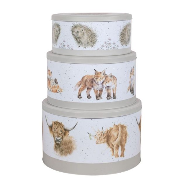 Three grey cake tins with illustrations of hedgehogs, foxes and highland cows on a white background