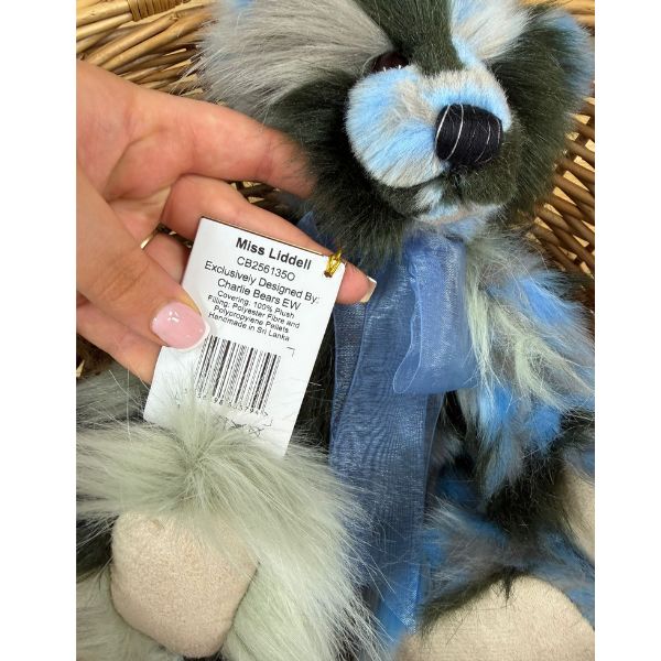 CB256135O Close-up of Charlie Bears Miss Liddell teddy bear holding label with product details