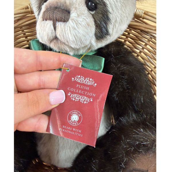 Charlie Bears CB252557 Close-up of Charlie Bears Botwood plush panda with product tag held by hand