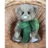Charlie Bears Mr Baggins plush bear sitting in wicker basket showing front view with green bow