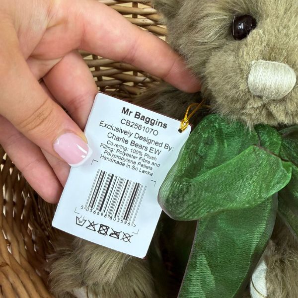 Mr Baggins CB256107O Charlie Bears Mr Baggins tag showing product details and washing instructions held next to bear